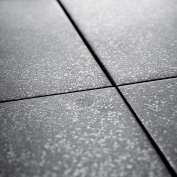 Graue Keramikfliesen kreuzen sich und bilden ein Gittermuster. Jede Fliese ist mit einer leichten Textur gesprenkelt, wodurch ei