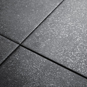 Vier dunkelgraue Fliesen weisen eine dezent gesprenkelte Textur auf. Sie sind eng aneinandergereiht und bilden bei künstlicher B