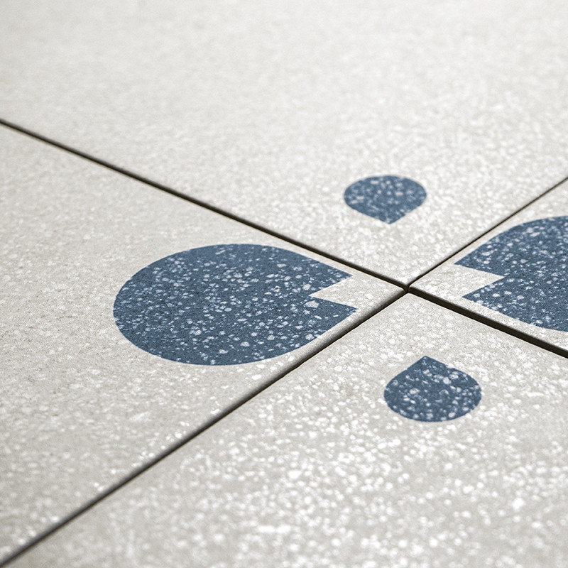 Les carreaux de céramique gris présentent des formes abstraites bleues ressemblant à des gouttelettes, disposées selon un motif 