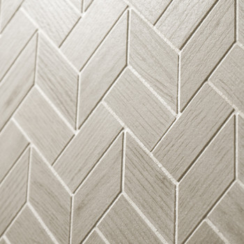 Beige tegels gerangschikt in een visgraatpatroon vormen een gestructureerd oppervlak, waardoor een geometrisch ontwerp ontstaat 