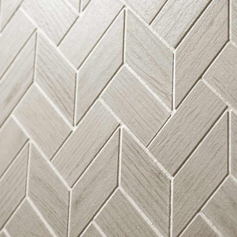 Beige tegels gerangschikt in een visgraatpatroon vormen een gestructureerd oppervlak, waardoor een geometrisch ontwerp ontstaat 