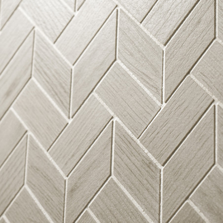 Beige tegels gerangschikt in een visgraatpatroon vormen een gestructureerd oppervlak, waardoor een geometrisch ontwerp ontstaat 