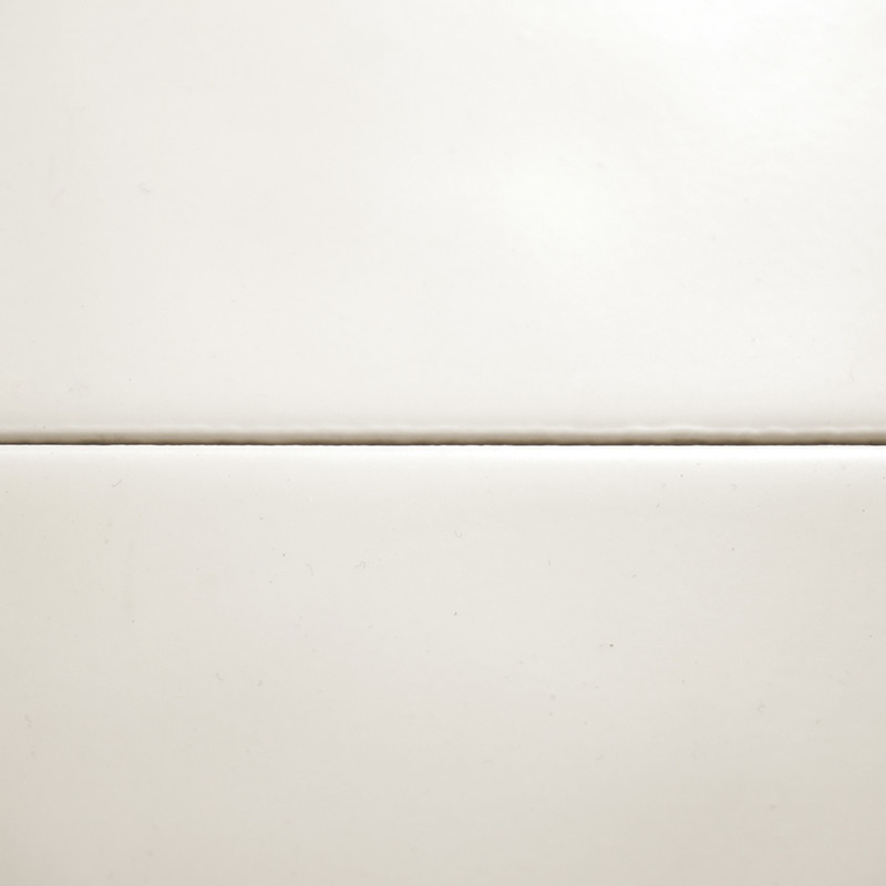 Dois ladrilhos brancos lisos, separados por uma fina linha de argamassa horizontal, formam uma superfície simples e limpa contra