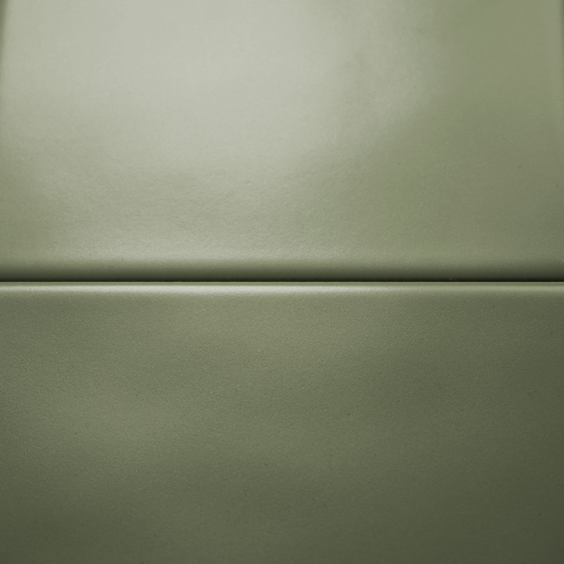 Two smooth, matte green tiles rest horizontally, separated by a thin, straight grout line, set against a seamless backdrop.