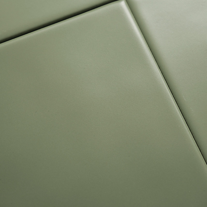 Keramikfliesen greifen in einem nahtlosen Muster ineinander. Die glatte, matte, olivgrüne Oberfläche sorgt für eine minimalistis