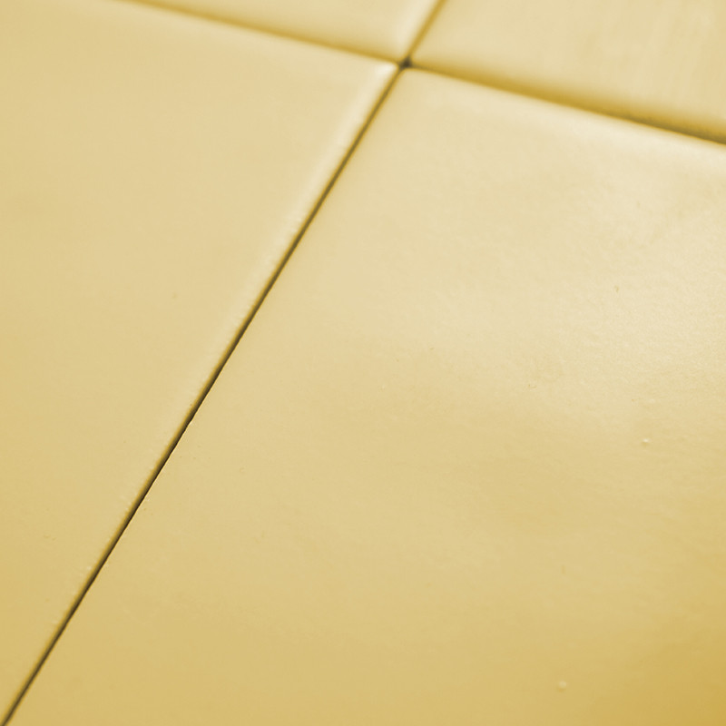 Quatro ladrilhos amarelos lisos formam uma grade, criando um padrão geométrico minimalista em uma superfície plana.