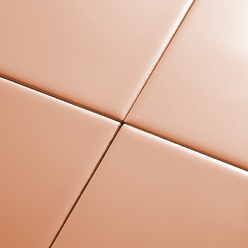 Quatre carreaux de céramique lisses de couleur pêche sont parfaitement alignés, formant un motif en grille avec des lignes de co
