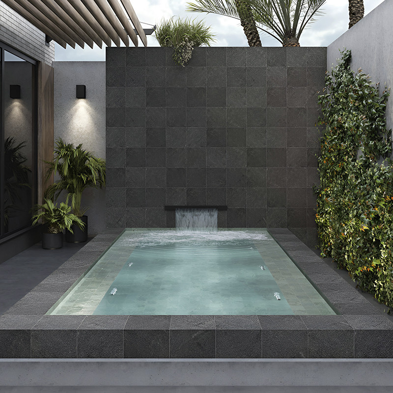 Os azulejos de pedra escura formam uma parede com água, com água caindo em cascata para uma pequena piscina retangular. ao redor Os azulejos de pedra escura formam uma parede com água, com água caindo em cascata para uma pequena piscina retangular. ao redor