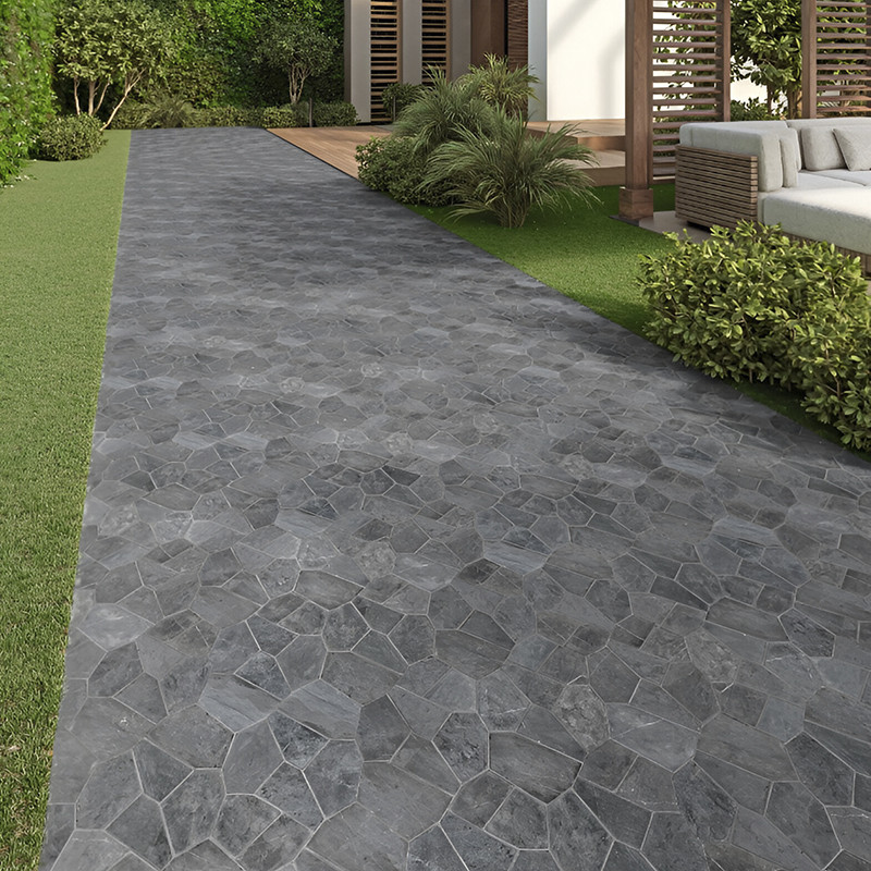 Grijze stenen tegels vormen een pad dat door een tuin met groene struiken en een moderne patio leidt.