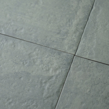 Four gray ceramic tiles form a grid, featuring a textured, stone-like surface. Subtle color variations suggest a natural slate a