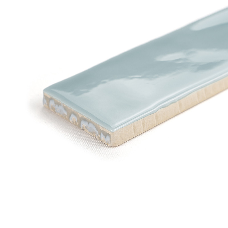 A rectangular ceramic tile with a glossy light blue surface rests on a plain white background, displaying its smooth, shiny fini
