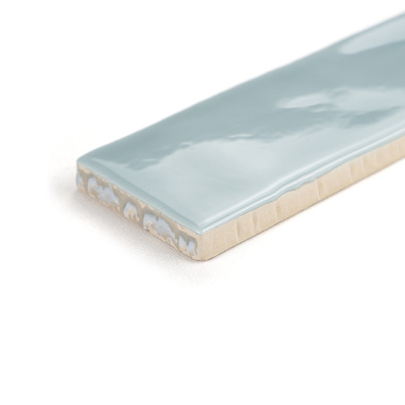 Eine rechteckige Keramikfliese mit glänzender hellblauer Oberfläche liegt auf einem schlichten weißen Hintergrund und zeigt ihre Eine rechteckige Keramikfliese mit glänzender hellblauer Oberfläche liegt auf einem schlichten weißen Hintergrund und zeigt ihre