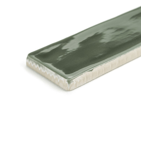 Eine rechteckige Keramikfliese, glänzend und grün, reflektiert Licht auf ihrer glatten Oberfläche. Seine Kanten zeigen eine natü