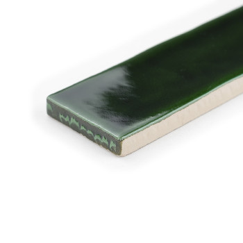 Eine rechteckige Fliese hat eine glänzende, dunkelgrüne Oberfläche, die das Licht dezent reflektiert, vor einem weißen Hintergru