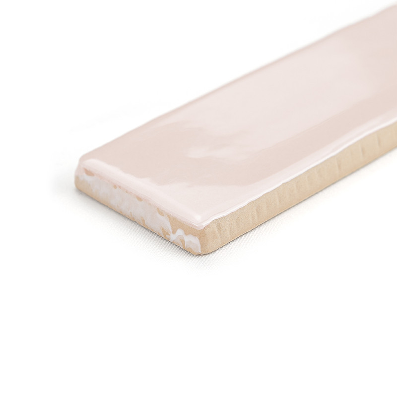 Un azulejo cerámico rectangular muestra una superficie brillante de color rosa claro con un borde biselado, sobre un fondo blanc