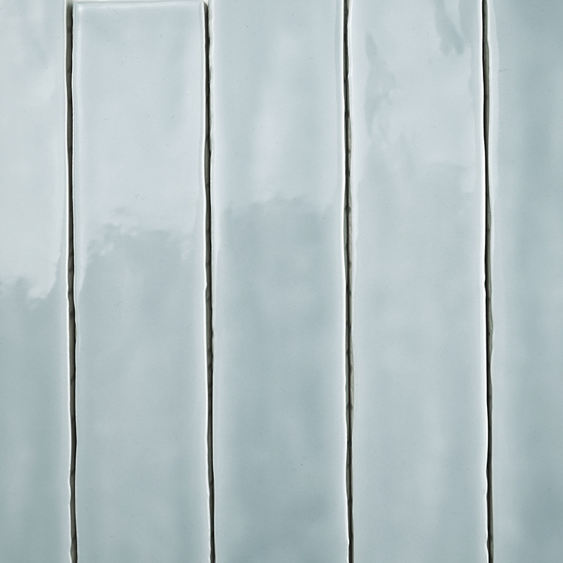 Les carreaux rectangulaires sont disposés verticalement dans une grille, avec une finition gris pâle brillante, reflétant subtil
