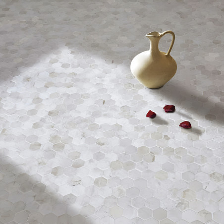 De keramische kan rust op zeshoekige stenen tegels, verlicht door zonlicht, vergezeld van verspreide rode rozenblaadjes.