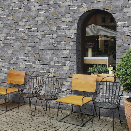 Stone tiles form a rustic wall, framing a large arched window, bordered by iron chairs and potted plants on a cobblestone path. Stone tiles form a rustic wall, framing a large arched window, bordered by iron chairs and potted plants on a cobblestone path.