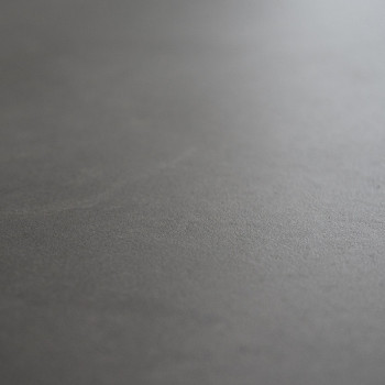 Eine schlichte, glatte graue Fliese liegt flach und weist eine subtile matte Textur auf, ohne sichtbare Muster oder umgebende Ob