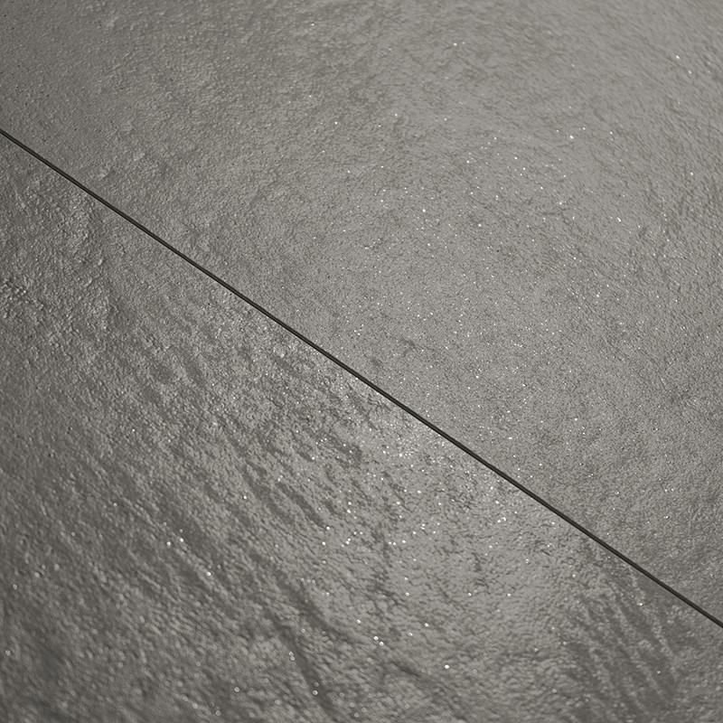 Gray stone tile with a subtle textured surface glistens under light, creating a natural appearance. fine grout line joins tiles 