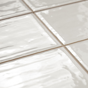 Witte keramische tegels vertonen een glanzend oppervlak met licht golvende texturen, gerangschikt in een netjes rasterpatroon op