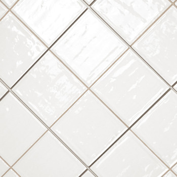 Carreaux de céramique blanche disposés en diagonale avec une finition brillante. les lignes de coulis forment un motif de grille