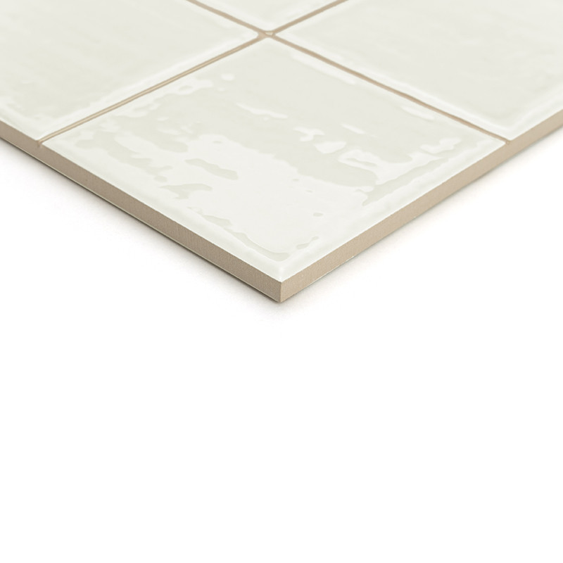 Un carreau de céramique beige au fini brillant, segmenté en quatre carrés plus petits, apparaît sur un fond blanc uni.