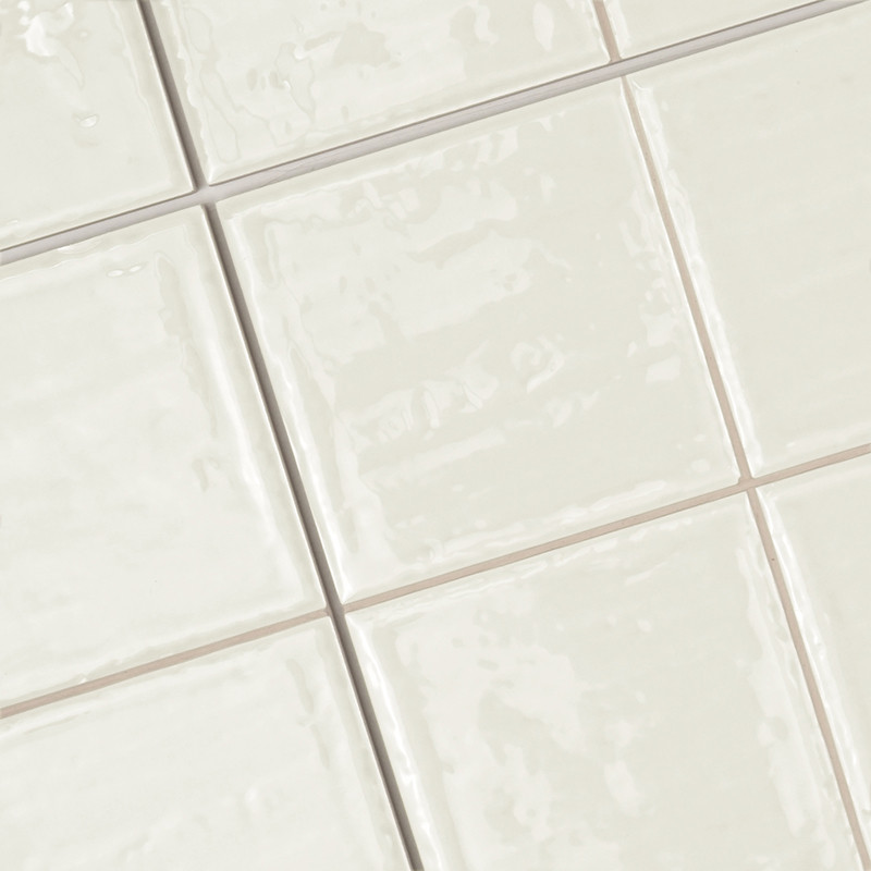 Les carreaux de céramique, disposés en quadrillage, présentent une surface beige clair brillante. Ils créent une surface de sol 