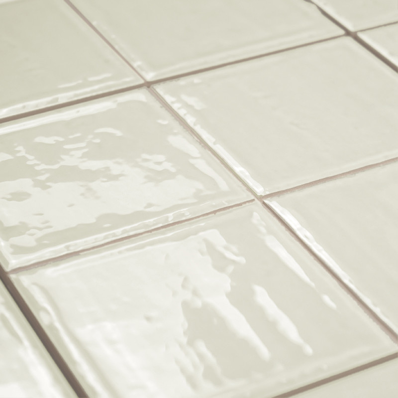 Carreaux carrés brillants blanc cassé disposés selon un motif en grille. ils réfléchissent la lumière, créant une surface élégan