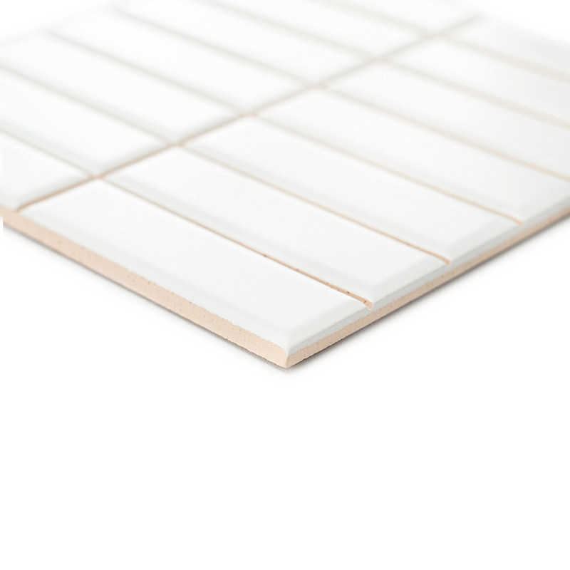 The object is a white ceramic tile with rectangular ridges, lying flat against a white background, creating a linear, geometric 