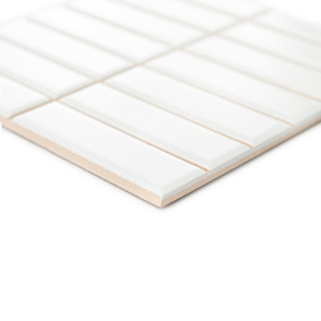 L’objet est un carreau de céramique blanche aux stries rectangulaires, posé à plat sur un fond blanc, créant un motif géométriqu