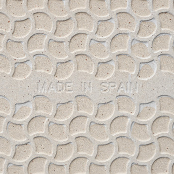 Tile features embossed, overlapping semicircular pattern. `MADE IN SPAIN` inscribed in center. Background is a light beige color