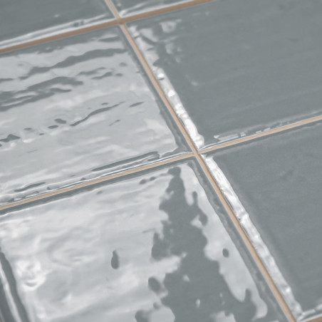 Glänzende graue Keramikfliesen sind in einem Gittermuster angeordnet, reflektieren das Licht und zeigen eine dezent wellige Text Glänzende graue Keramikfliesen sind in einem Gittermuster angeordnet, reflektieren das Licht und zeigen eine dezent wellige Text
