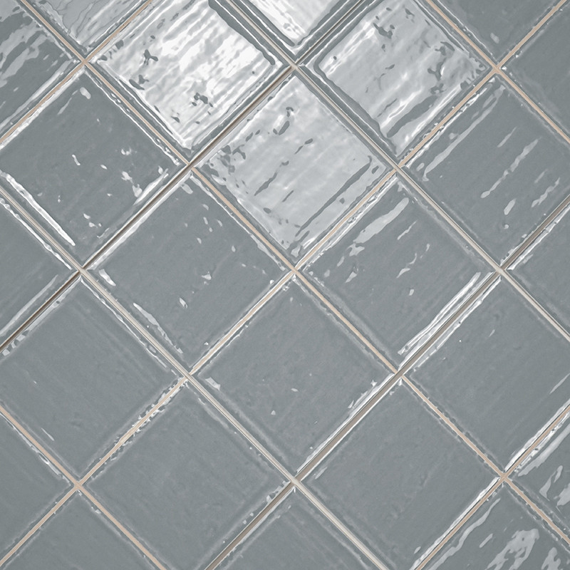 Grijze keramische tegels gerangschikt in een diagonaal rasterpatroon, reflecterend licht, creëren een glanzend, gestructureerd u
