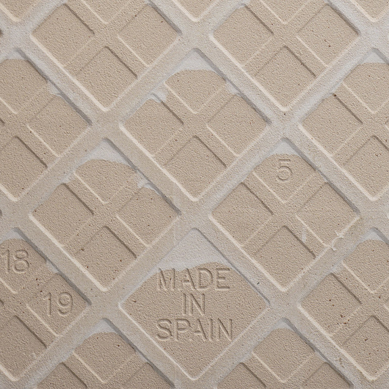 Azulejo cerâmico bege com padrão de grade de diamante, apresentando texto em relevo `MADE IN SPAIN` no centro e números nos cant
