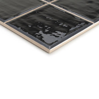 Um ladrilho cerâmico preto brilhante apresenta uma superfície texturizada, refletindo a luz sutilmente. Encontra-se inclinado so