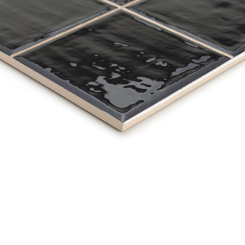 Um ladrilho cerâmico preto brilhante apresenta uma superfície texturizada, refletindo a luz sutilmente. Encontra-se inclinado so