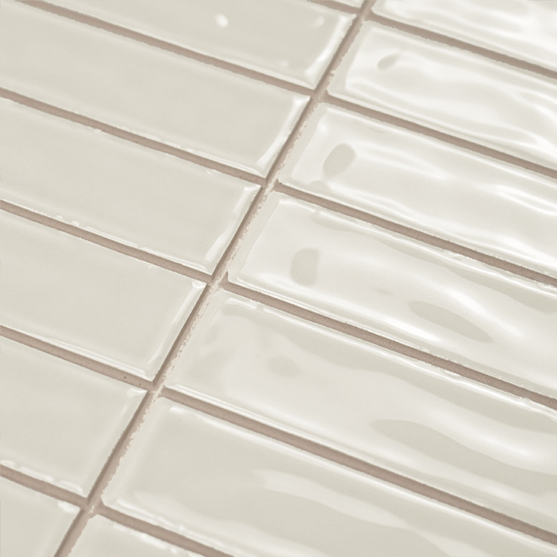 Rectangular ceramic tiles with a glossy finish are aligned in a staggered pattern, creating a wavy texture in a neutral-colored 