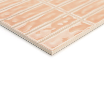 Een rechthoekige, perzikkleurige keramische tegel heeft een glanzend, golvend oppervlaktepatroon. Het is gerangschikt in een ras