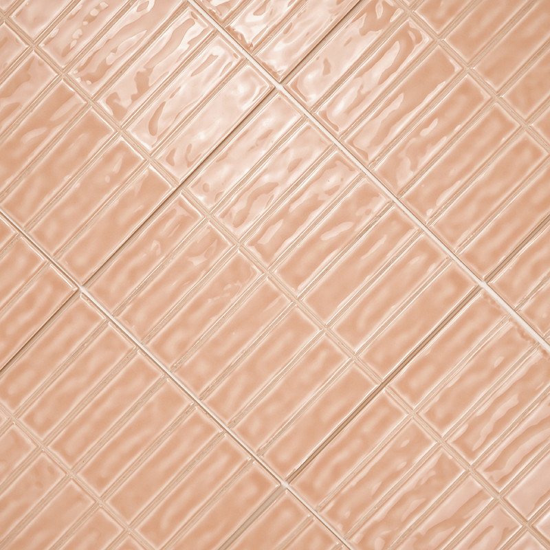 Los azulejos rectangulares de color melocotón están dispuestos en diagonal, creando un patrón reflectante ondulado sobre una sup