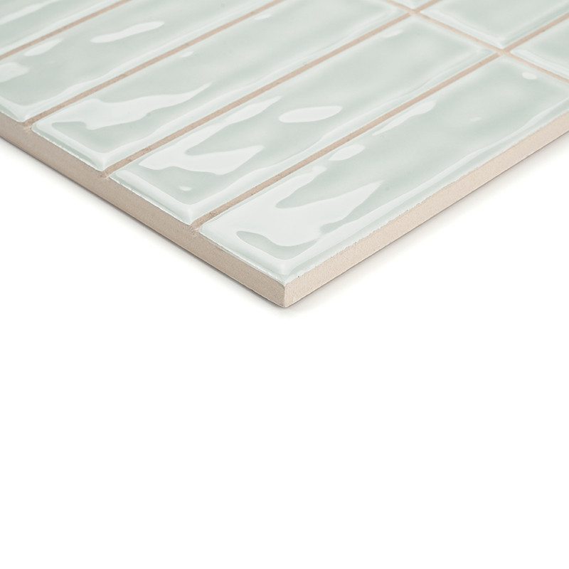 Une grille rectangulaire de carreaux vert pâle brillants, séparés par de fines lignes de coulis, repose sur une surface de suppo