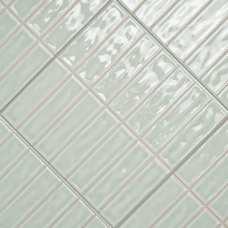 Les carreaux de céramique rectangulaires, disposés en diagonale, présentent une surface brillante vert clair avec une subtile te