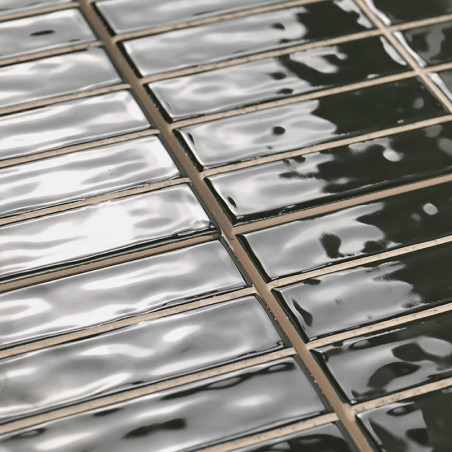 Rechteckige Fliesen, glänzend und dunkel, liegen in gleichmäßigen Reihen. Auf ihren glatten Oberflächen wird Licht reflektiert u