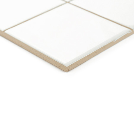 Een keramische tegel met een glanzend wit oppervlak ligt op een beige basis en maakt deel uit van een raster in een minimalistis