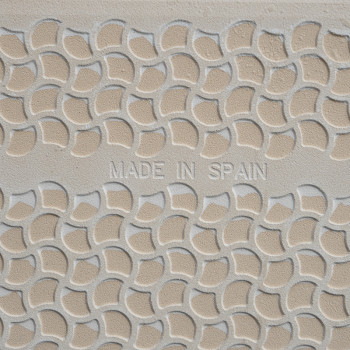A beige tile displays a raised, semi-circular pattern in a repeating geometric design. The central text reads `MADE IN SPAIN.`