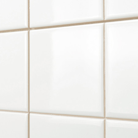 Les carreaux de céramique blancs et brillants sont disposés en grille, créant une surface lisse et réfléchissante. Les carreaux 