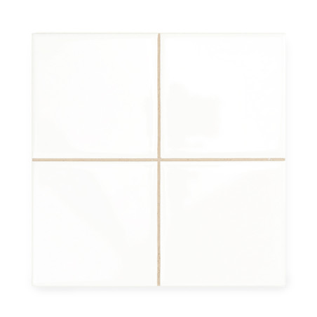 Cuatro azulejos de cerámica blanca y lisa están alineadas formando un cuadrado más grande. Finas líneas de lechada de color beig