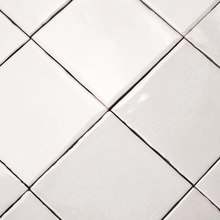 Les carreaux de céramique carrés s'alignent dans une grille, créant un motif homogène sur une surface plane, avec de légères var