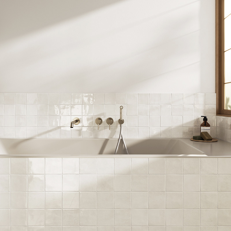 Les carreaux de céramique blanche forment une toile de fond épurée et brillante dans une salle de bain. Un robinet de baignoire 