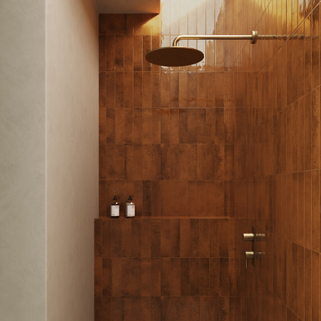 Ein bronzener Duschkopf ragt aus einer gefliesten Wand und verströmt imaginäres Wasser in einem modernen Badezimmer mit bernstei